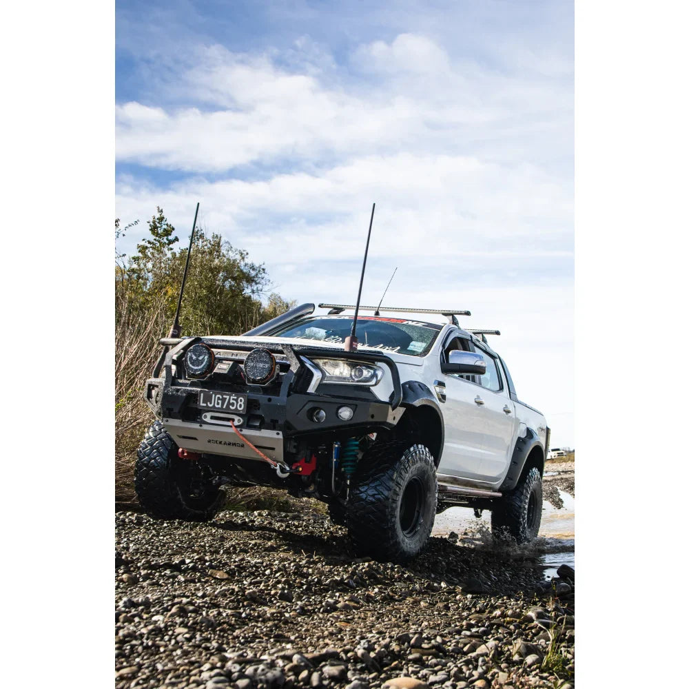 White pickup truck with off-road modifications featuring a bull bar and driving lights
